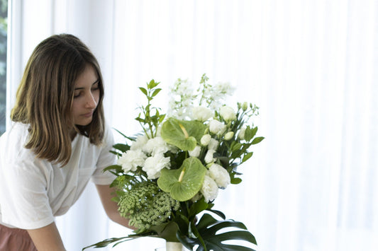 A white Fig and Bloom arrangement being placed in a calm, light-filled room