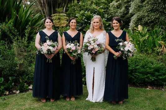 A bride and her bridesmaids holding soft summer bouquets in a lush Australian garden