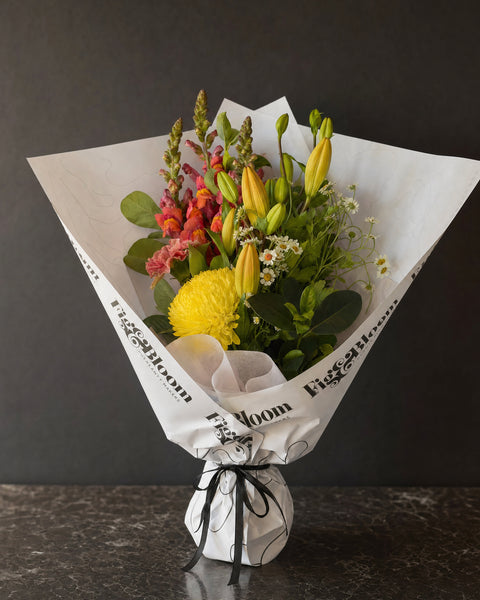 Amalfi Posy by Fig & Bloom: lilies, coral snapdragon and yellow disbud, hand-tied in printed paper