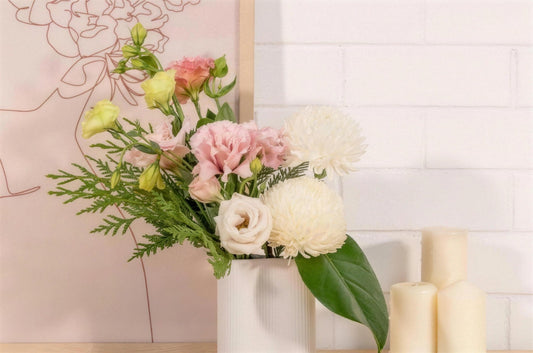 A calm pink and white arrangement at home beside cream candles and a line-art print