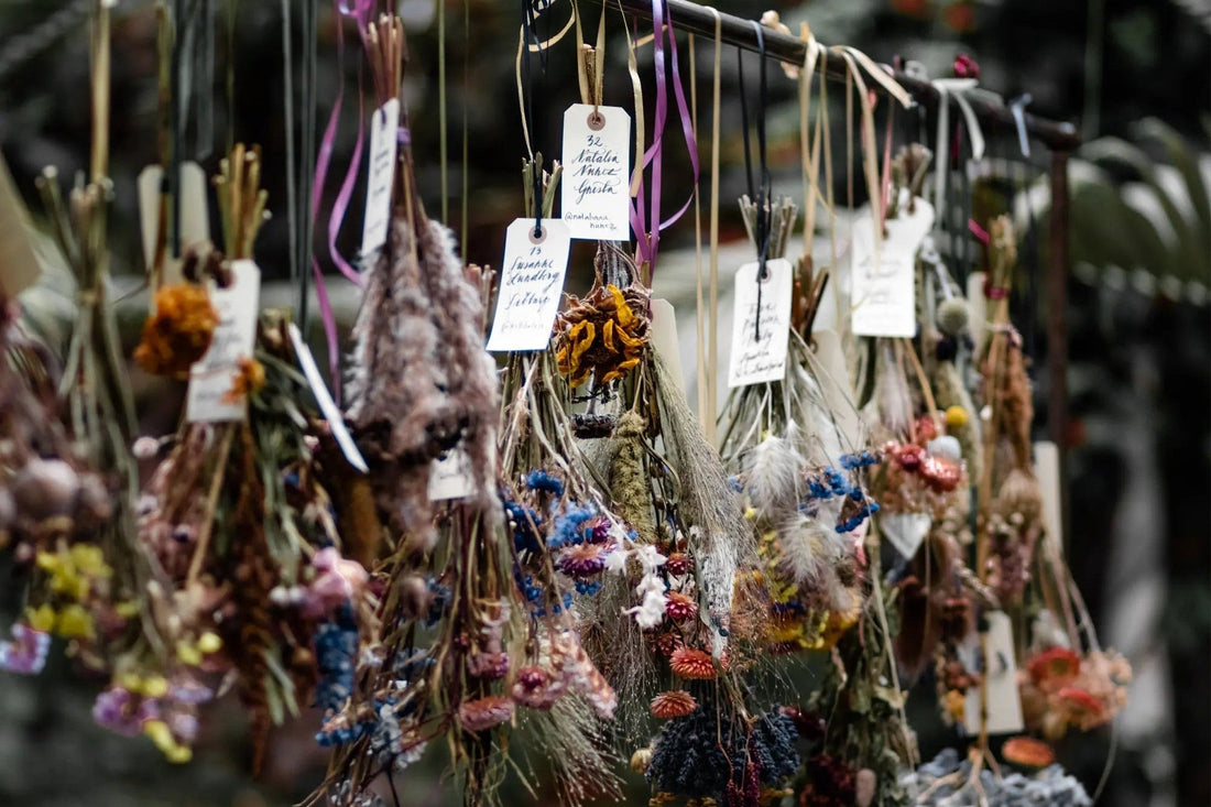 Bunches of flowers hanging upside down to dry, tagged and spaced along a rail