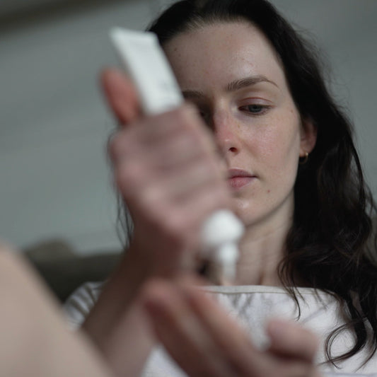 A woman applying a Salus product close to her face, in soft natural light
