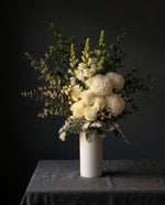Lucerne arrangement in its white ceramic vase on a linen-covered table