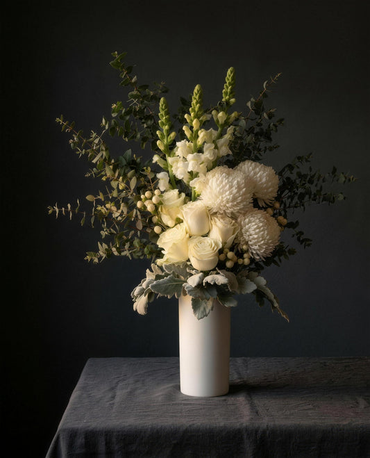 Lucerne arrangement in its white ceramic vase on a linen-covered table
