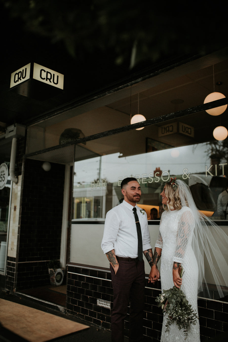 Bride and groom outside Cru wine bar in Melbourne, the bride holding her protea bouquet