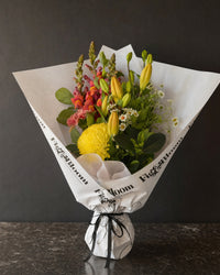 Amalfi Posy by Fig & Bloom: lilies, coral snapdragon and yellow disbud, hand-tied in printed paper