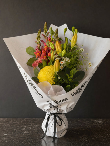 Amalfi Posy by Fig & Bloom: lilies, coral snapdragon and yellow disbud, hand-tied in printed paper