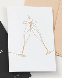 Champagne greeting card by Fig & Bloom, gold foil clinking champagne glasses line illustration with envelope