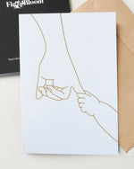 New Beginnings greeting card by Fig & Bloom, gold foil illustration of a baby hand holding an adult hand