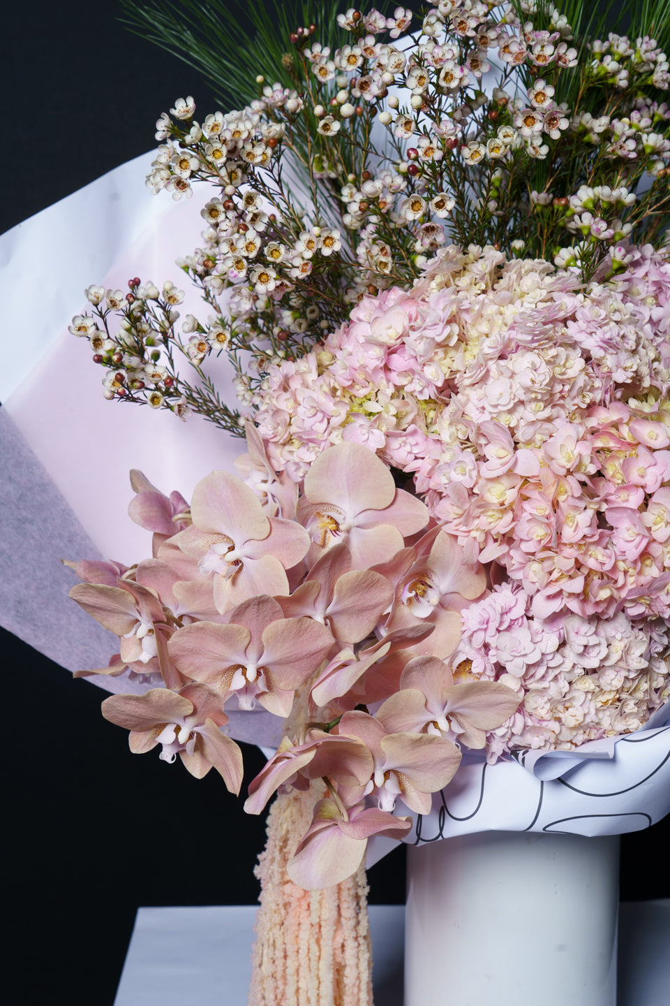 Close detail of the Carmen arrangement: blush hydrangea, apricot phalaenopsis and trailing amaranthus
