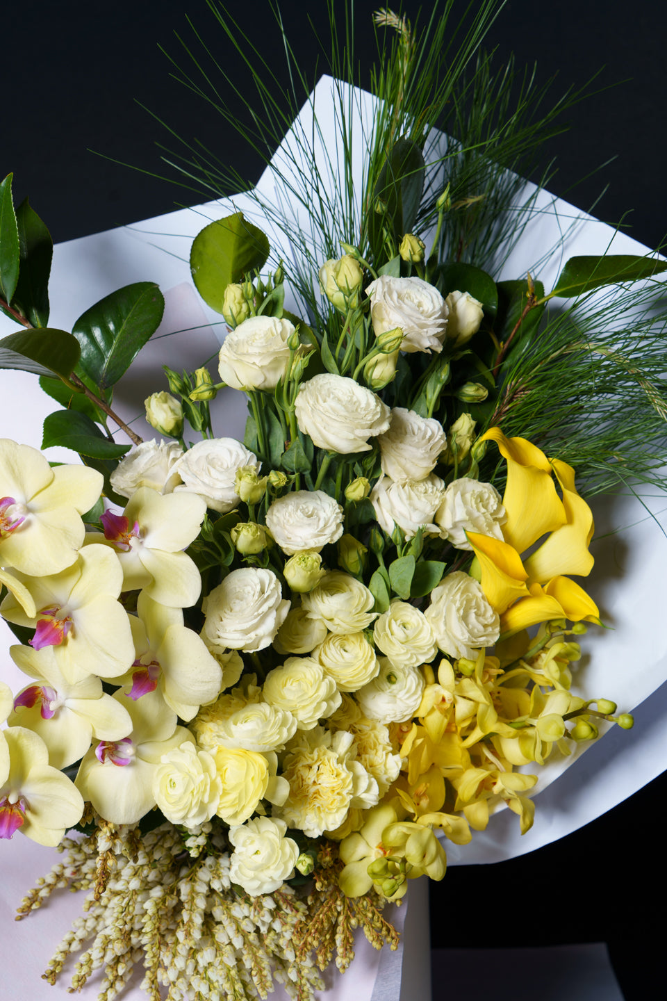 Soleil arrangement seen from above: pale yellow orchids, white roses and cream blooms