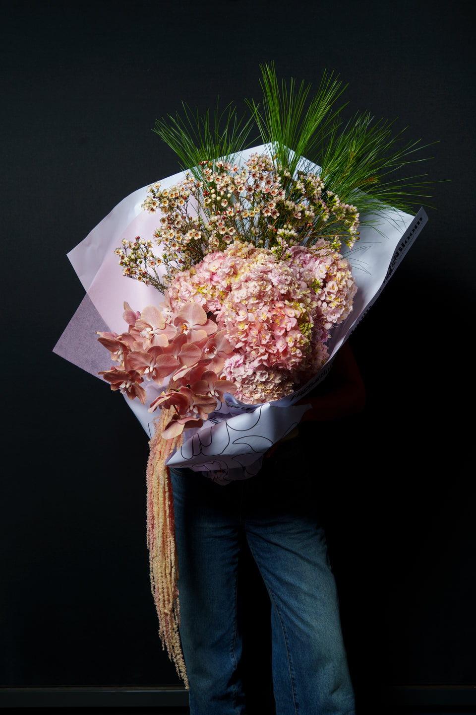 Model holding the Carmen arrangement against black, amaranthus trailing below