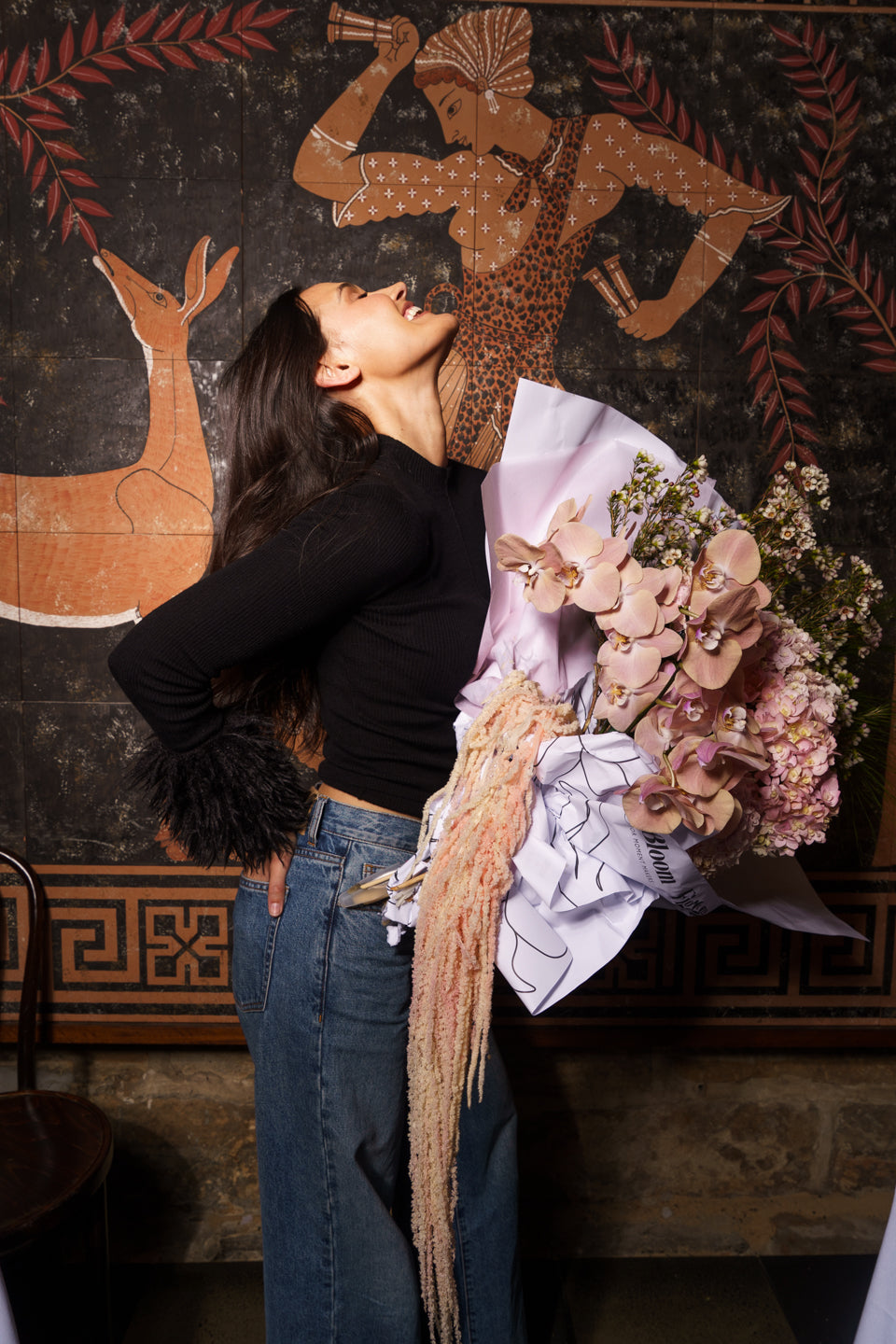 Model with head tipped back holding the Carmen arrangement against a painted mural