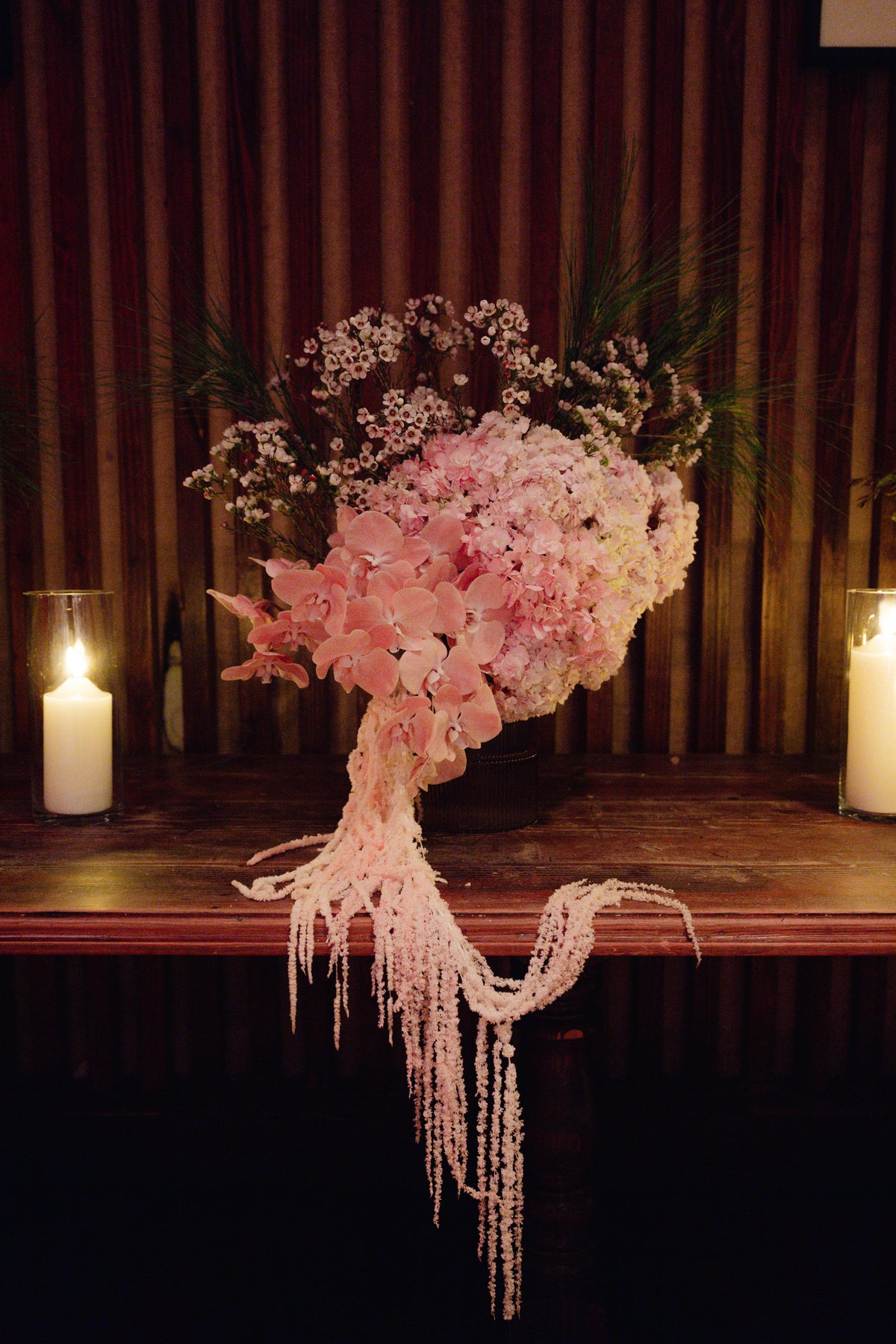 Carmen installation of blush hydrangea and trailing amaranthus lit by candles on the stage