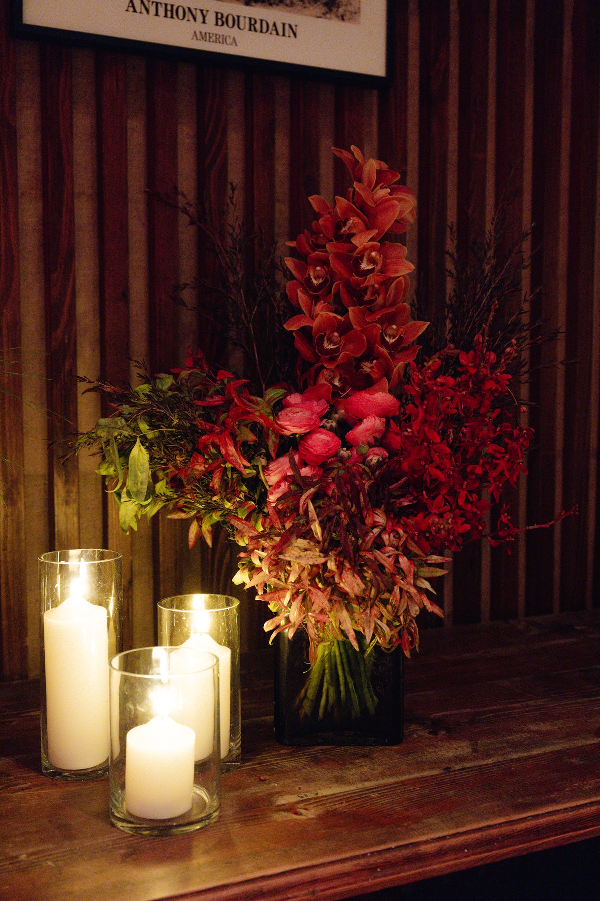 Sienna arrangement of rust and red blooms beside pillar candles