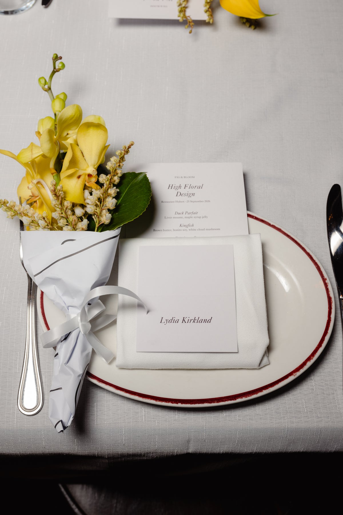 Place setting with a yellow orchid posy, menu and name card