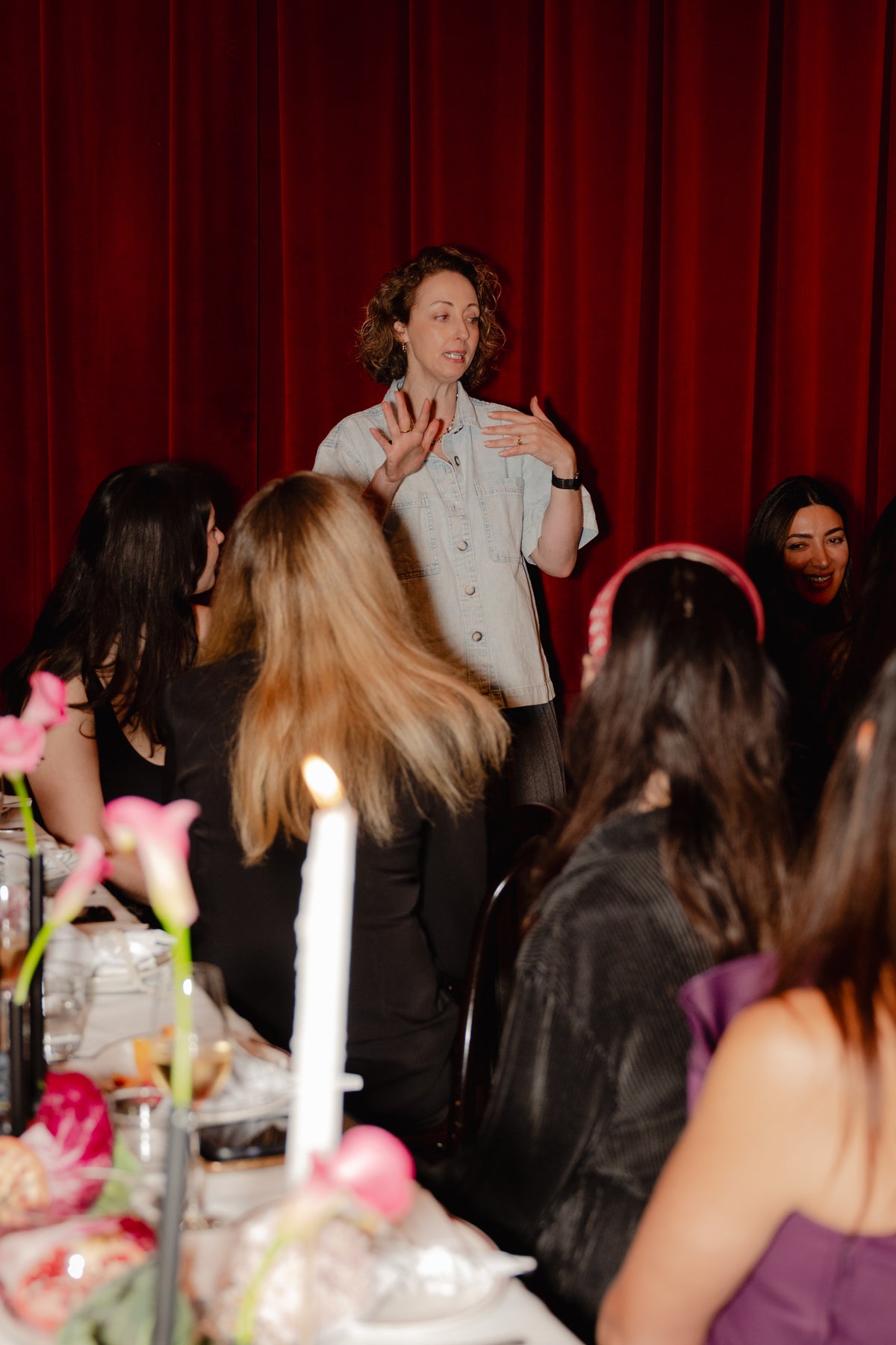 Kellie Brown speaking to guests across the candlelit lunch table