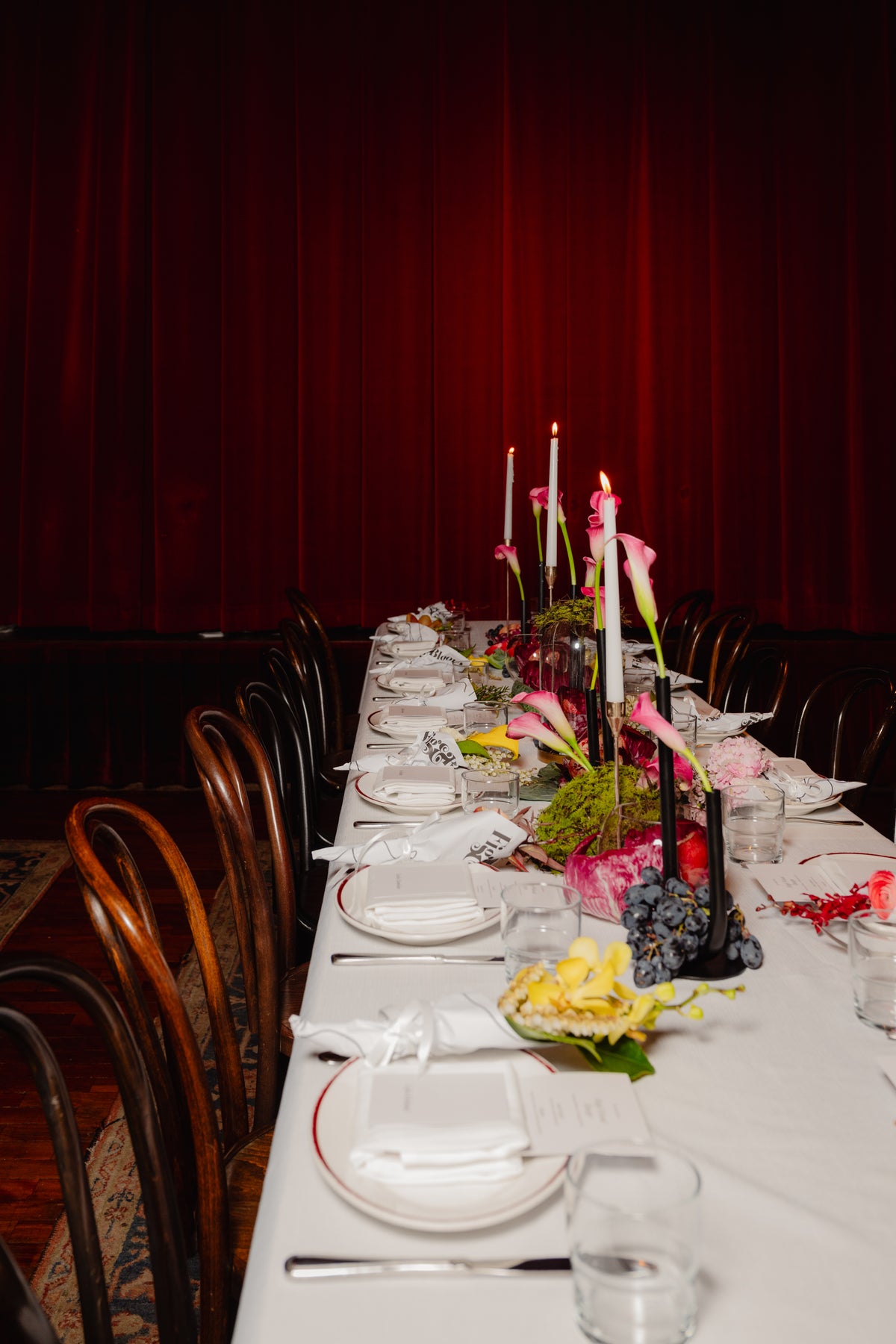 Long lunch table set with taper candles and pink calla lilies