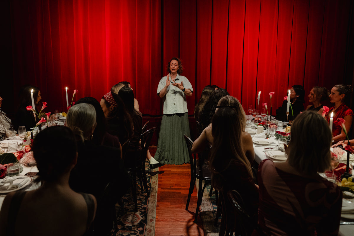 Speech to guests seated at the long lunch tables under the red curtain
