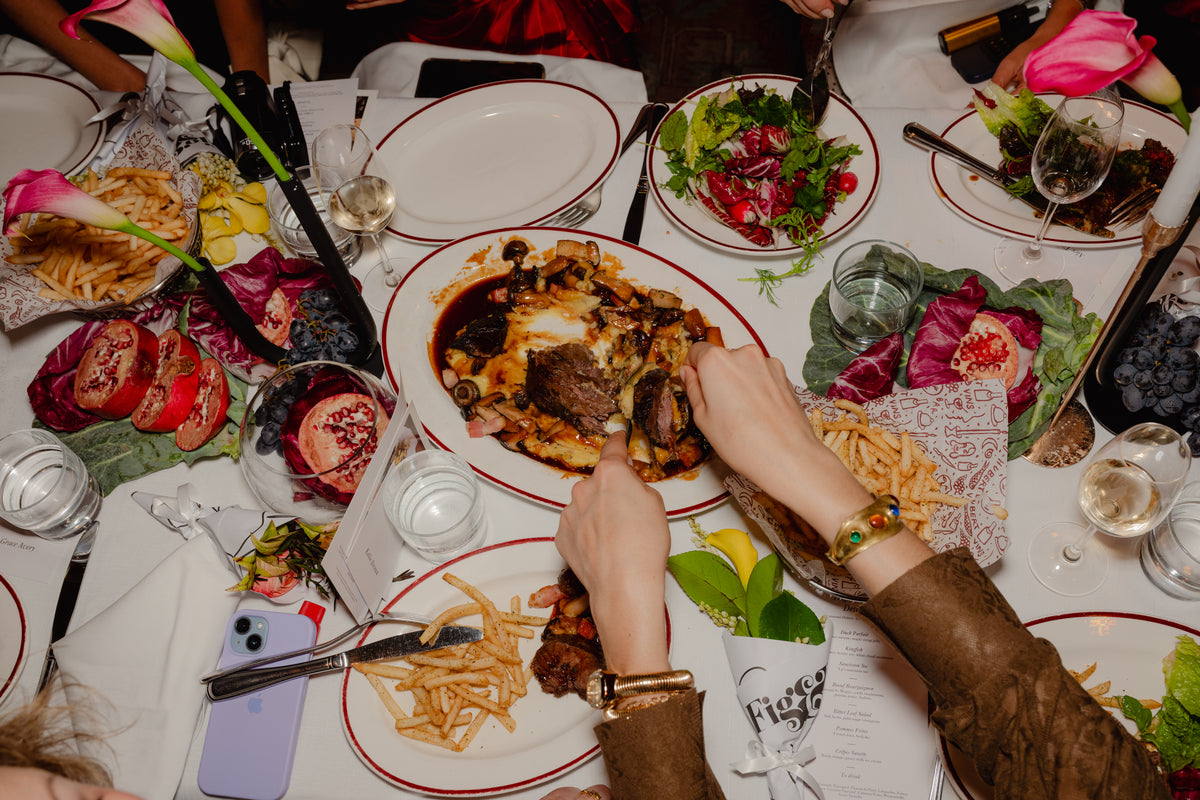 Overhead view of shared French plates, frites and florals along the lunch table