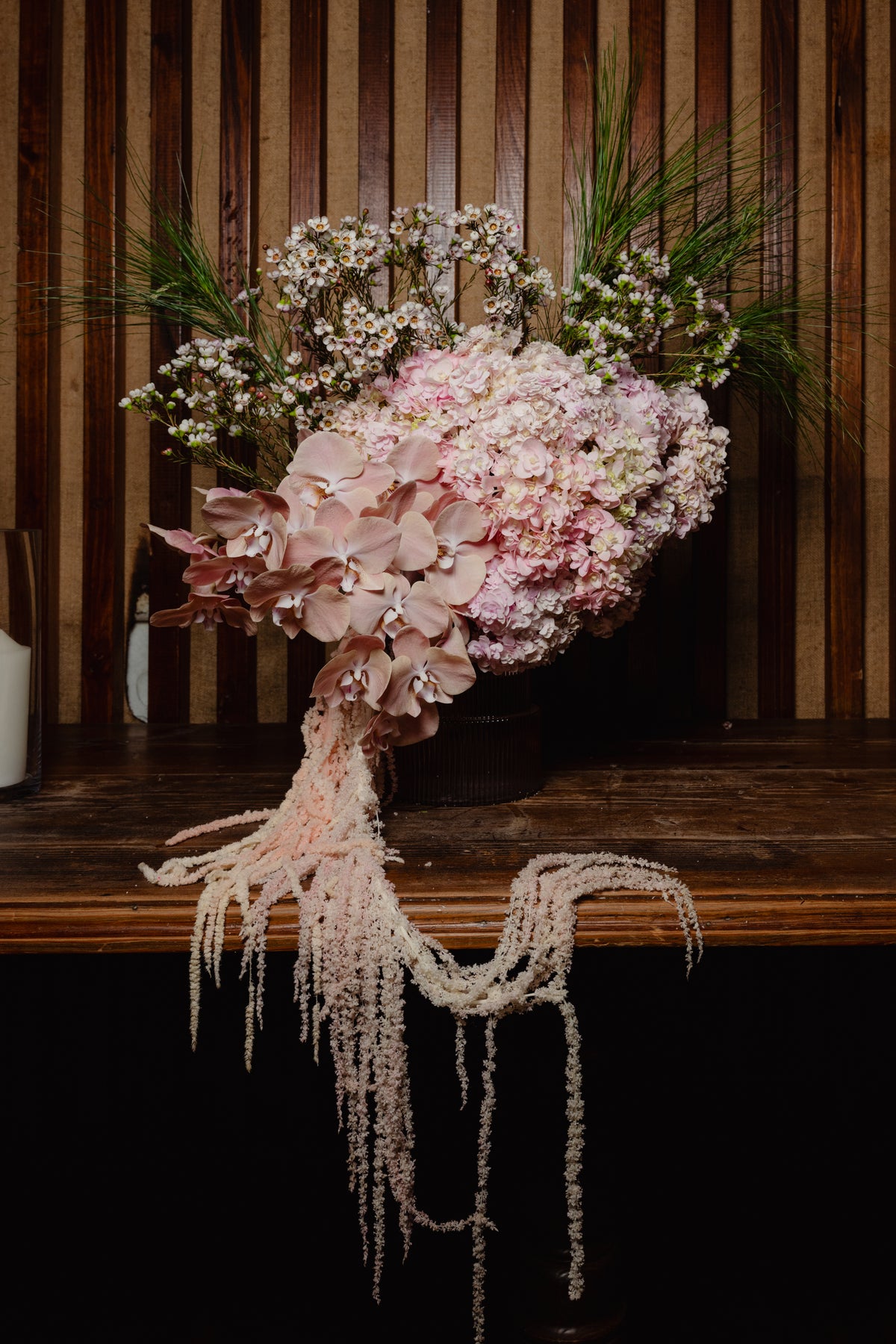 Carmen arrangement of blush hydrangea with amaranthus trailing from the bench