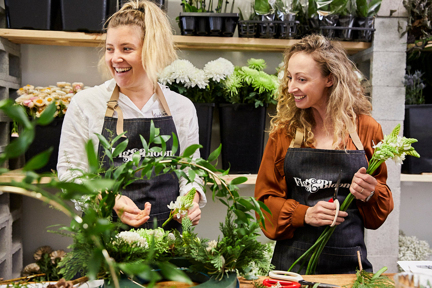 Kellie Brown and a Fig & Bloom florist holding greenery at a wreath-making workshop