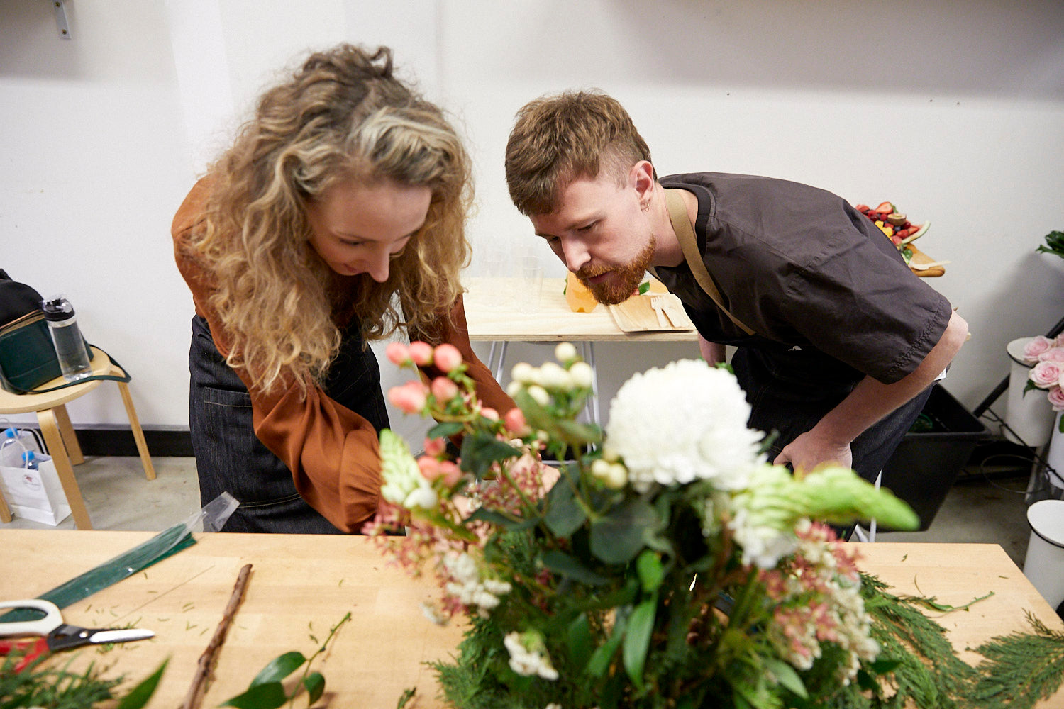 Kellie Brown leaning over a white and green arrangement at a Fig & Bloom floristry workshop