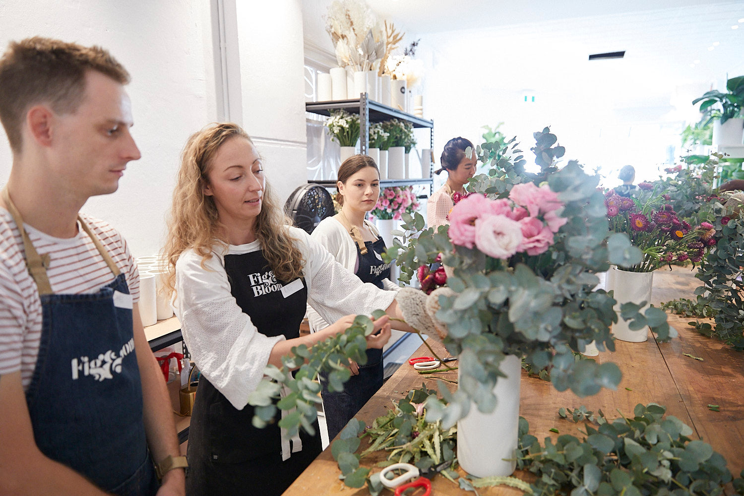 Kellie Brown helping participants arrange roses and eucalyptus at a Fig & Bloom workshop bench