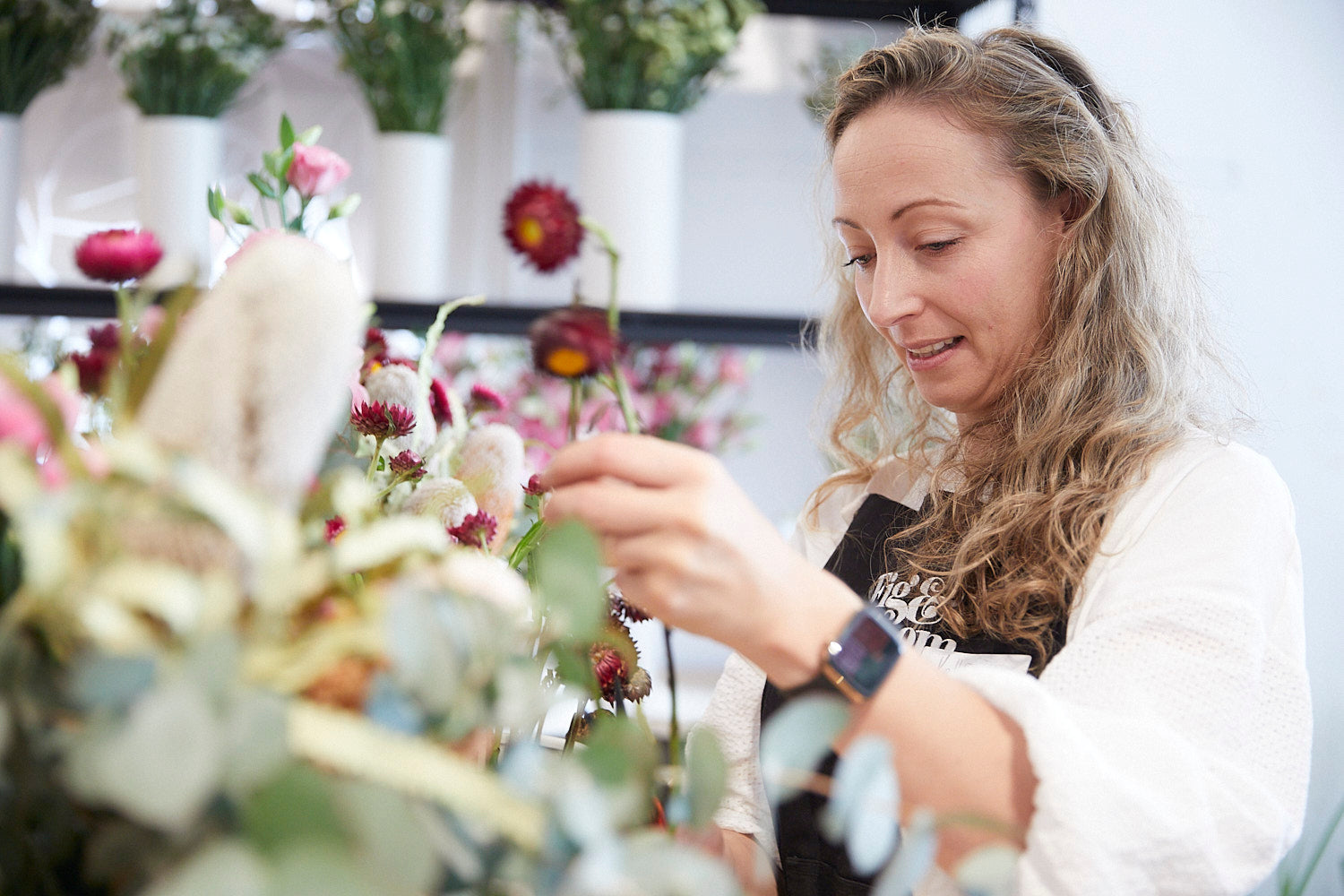 Kellie Brown holding a strawflower stem while building an arrangement at a workshop