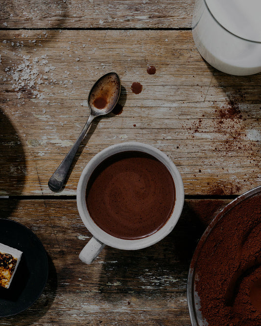 Overhead view of a cup of Mörk dark drinking chocolate with cacao powder, milk and a marshmallow