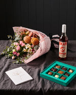 The Aperitif gift set laid on charcoal linen with Okar Bitter, chocolates and the Single Stem greeting card