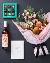 The Aperitif gift set flat lay on slate: bouquet, Okar Bitter, Koko Black chocolates and the Single Stem greeting card
