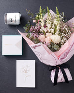 The Fuss photographed from above on charcoal slate: the Osaka Gesture bouquet, candle, Koko Black chocolates and greeting card.