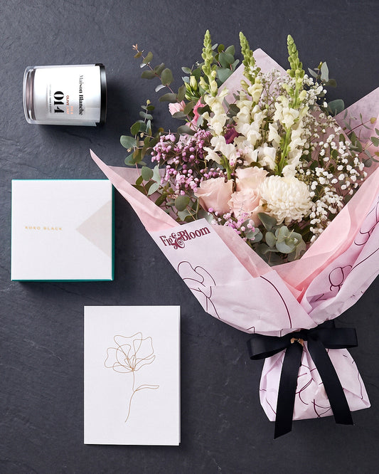 The Fuss photographed from above on charcoal slate: the Osaka Gesture bouquet, candle, Koko Black chocolates and greeting card.