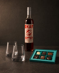 The Host gift bundle on charcoal: Stolzle Revolution tumblers, Okar Bitter aperitivo and Koko Black pralines