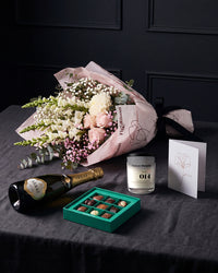 The Lot resting on charcoal linen in window light, with House of Arras, the Koko Black nine-piece selection, the candle and the greeting card alongside.