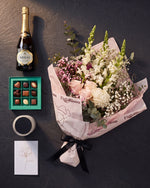 The Lot photographed from above on charcoal slate: the Osaka bouquet, House of Arras, Koko Black chocolates, the candle and the greeting card.