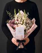 The Lot, the Osaka bouquet held at chest height with the greeting card tucked into the wrap, against a charcoal backdrop.