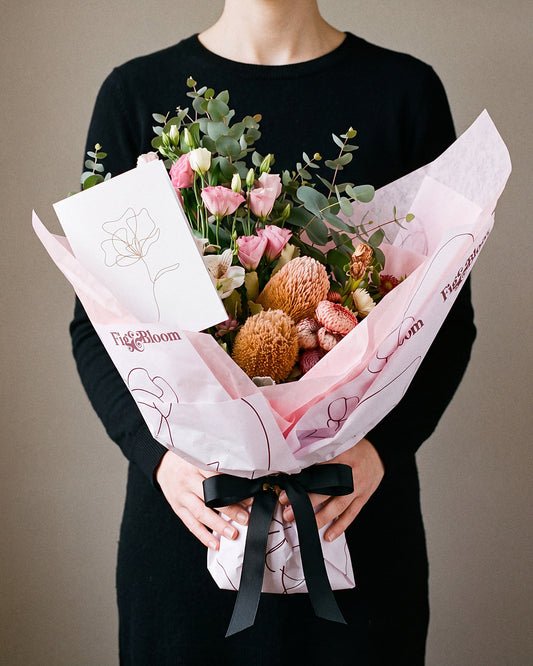 The Nightcap bouquet held at chest height with the Single Stem greeting card tucked into the wrap