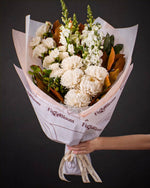 The Toast, the Pyrenees bouquet held out by one hand against a charcoal backdrop.