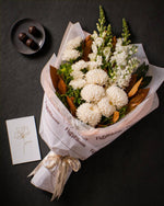 The Toast, the Pyrenees bouquet and a plate of dark chocolate marbles, photographed from above on charcoal slate with the greeting card alongside.