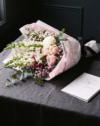 The Wish, the Osaka Gesture bouquet resting on charcoal linen in window light, with the greeting card alongside.
