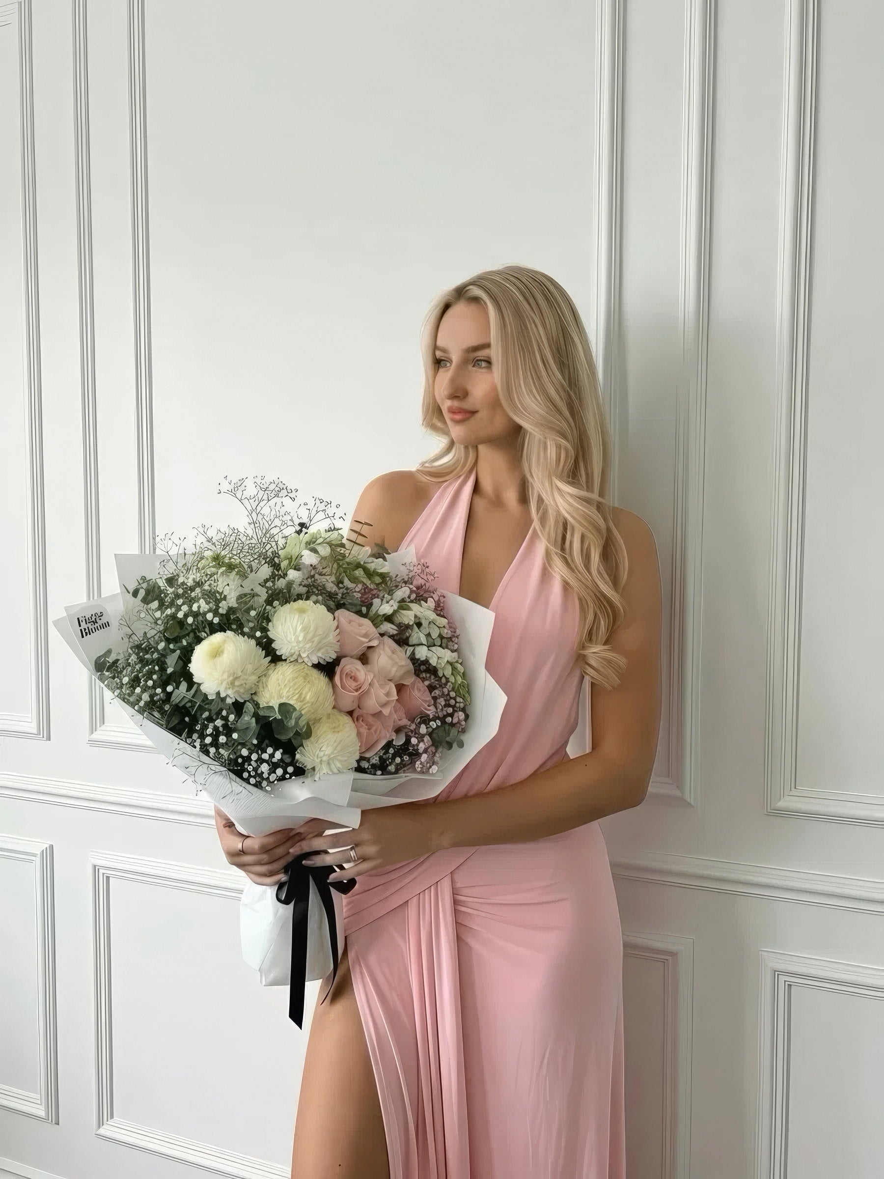 Woman in a pink dress holding a soft pink and white Fig & Bloom bouquet