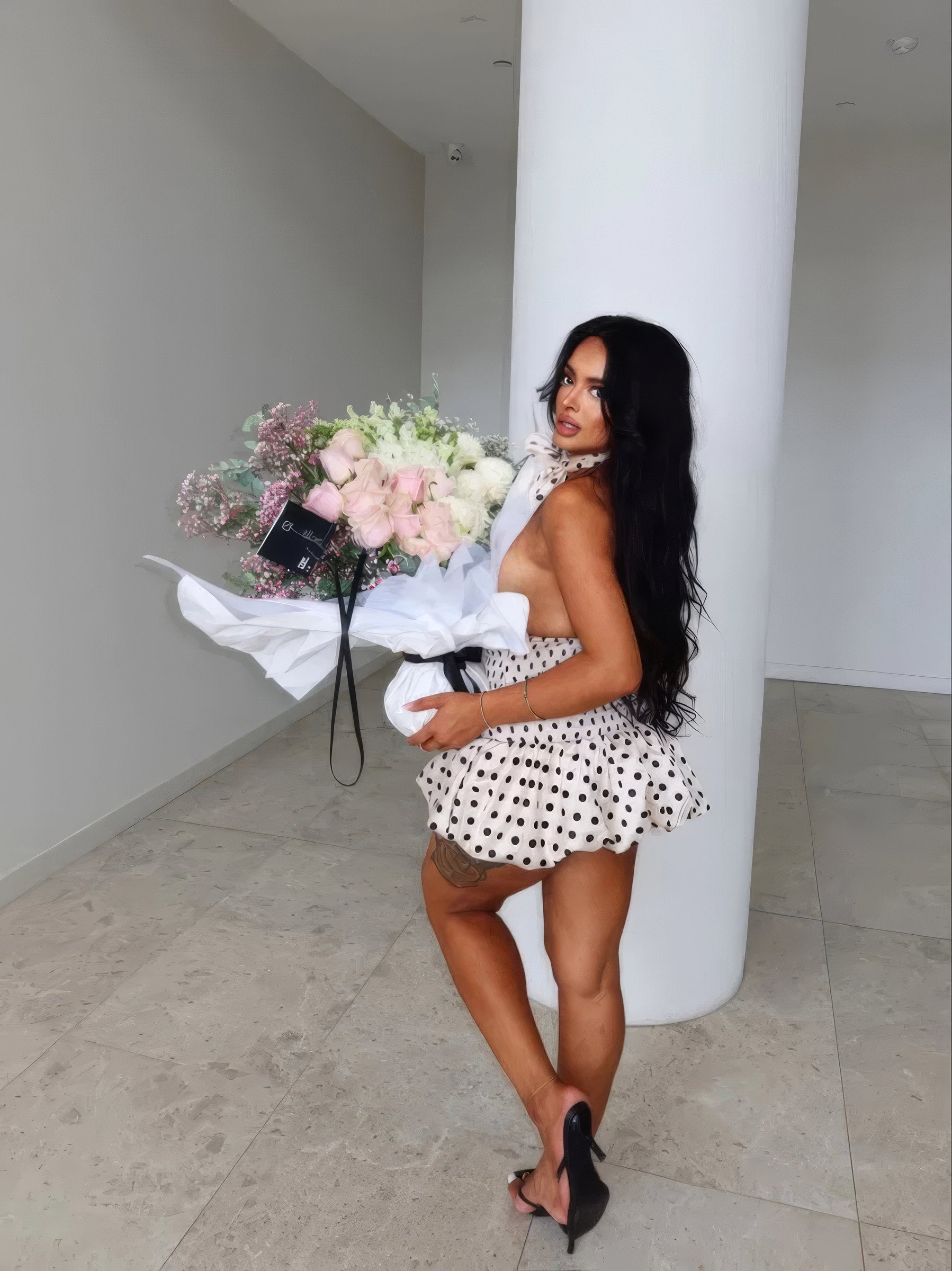 Woman in a polka-dot dress holding a pastel Fig & Bloom rose bouquet