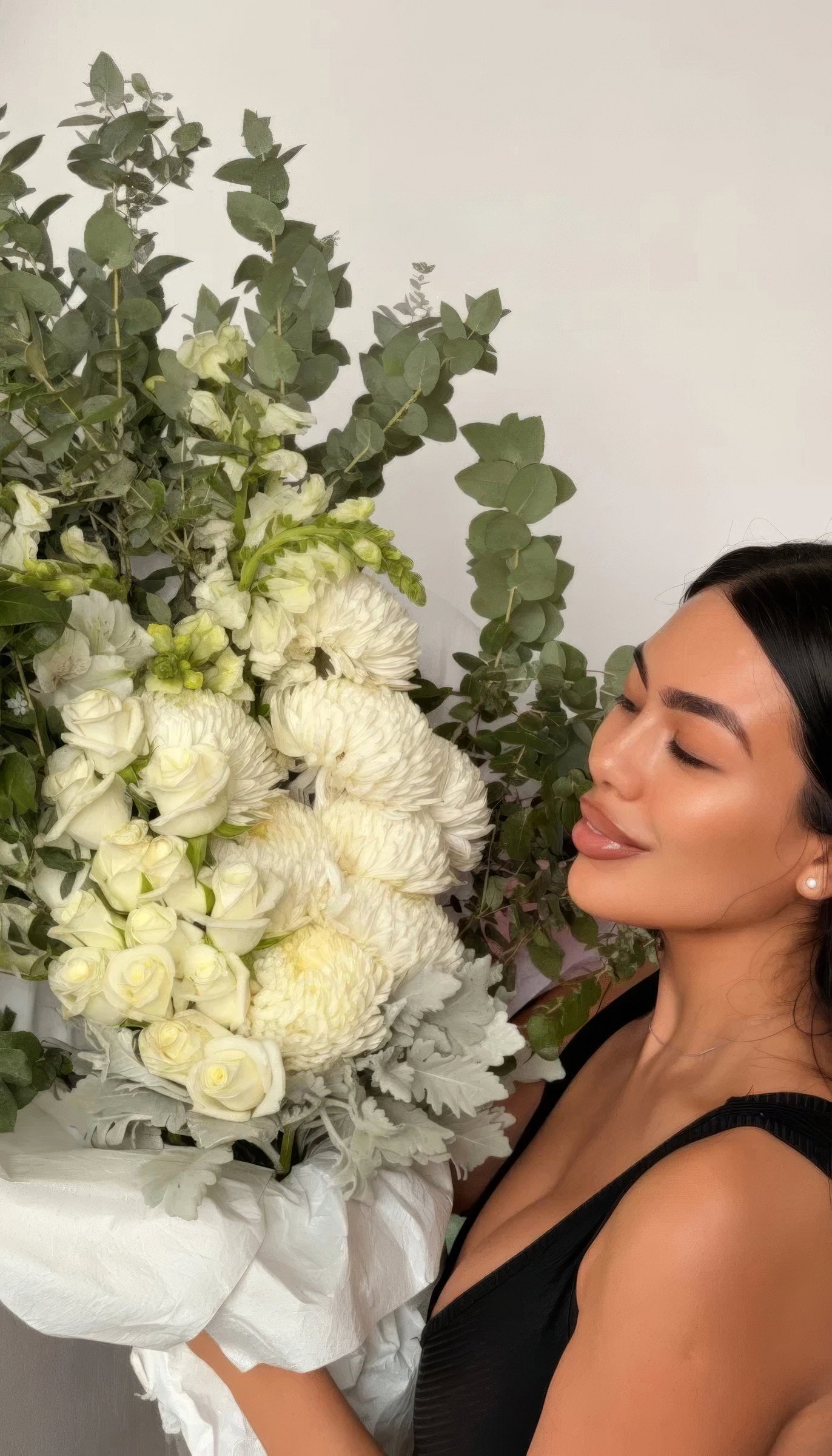 Woman in black holding an oversized white and green Fig & Bloom bouquet