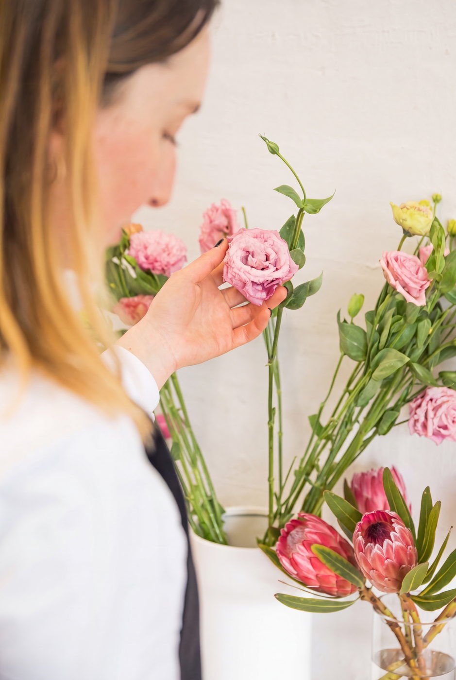 Florist inspecting a pink lisianthus flower while arranging stems