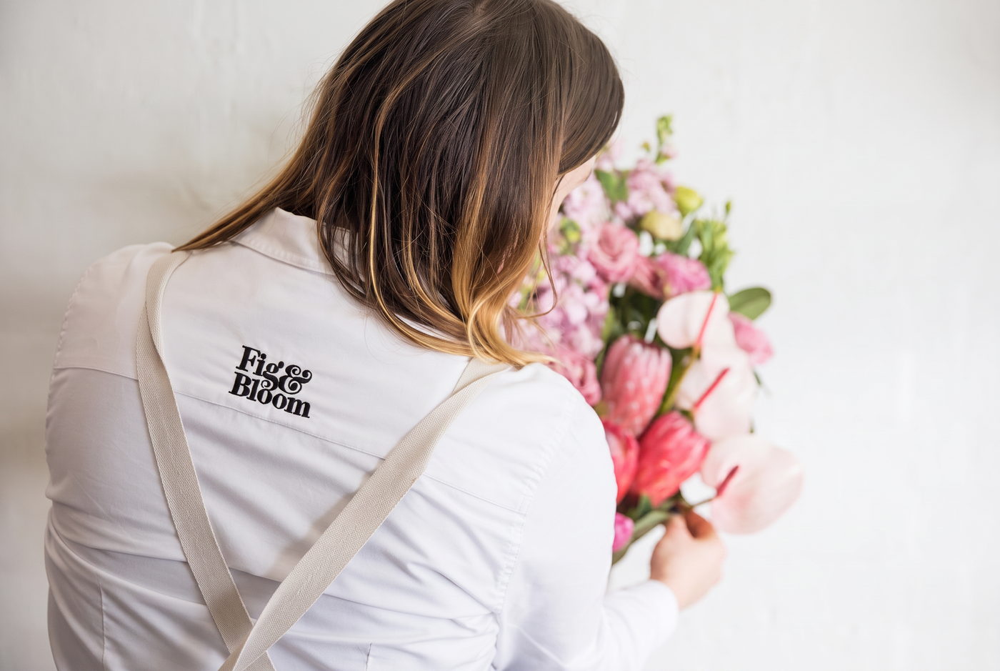 Fig & Bloom florist arranging pink flowers in the studio