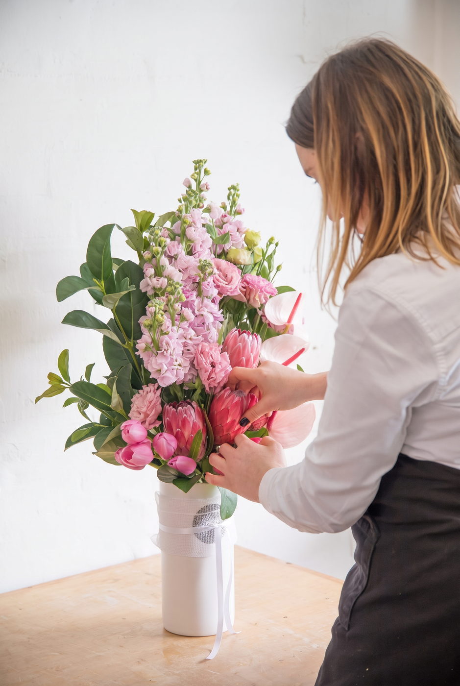 Florist arranging pink flowers in a white vase