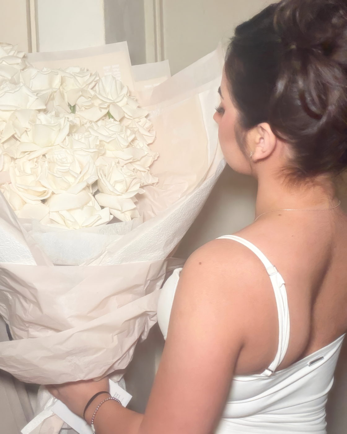 Woman in side profile holding an oversized bouquet of white roses